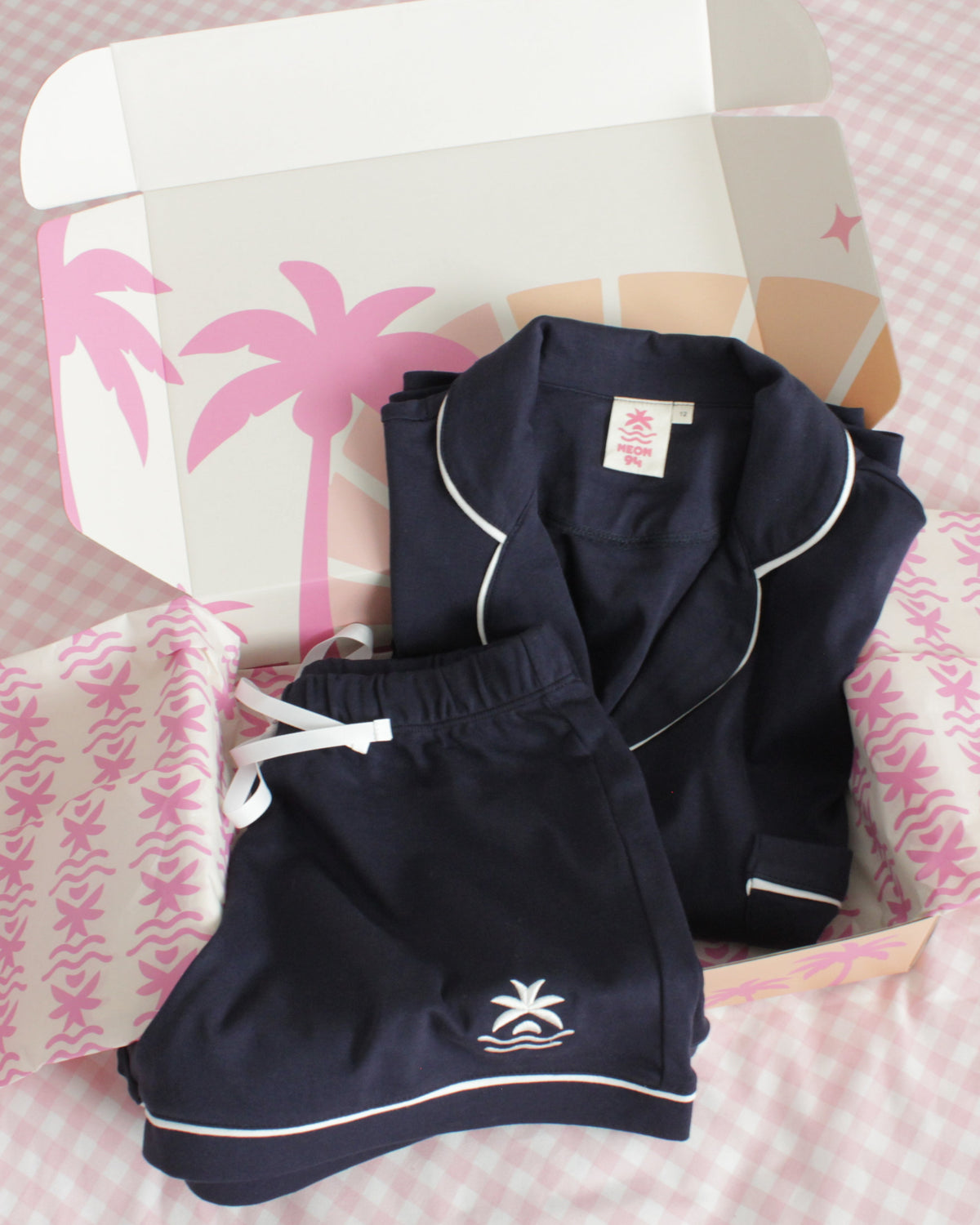 Neon94 Jellybean navy Sleepover Set folded in its Neon94 gift box with palm-print tissue paper